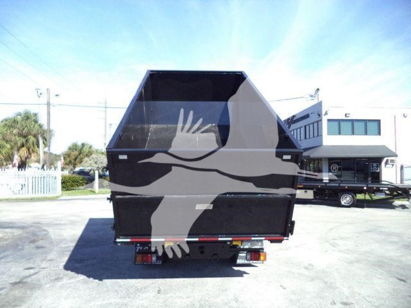 Isuzu NPRR roll-off truck rear view showing dumping bed and taillights.