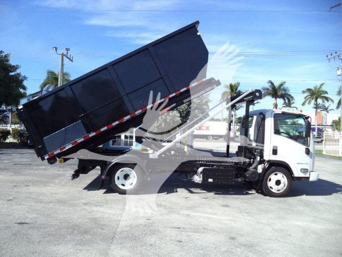 Isuzu NPR/NRR medium-duty truck with a tipped-box roll-off style bed in a raised position; cab white, dump bed black, hydraulic arms visible.