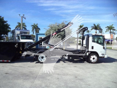 Isuzu NPR/NRR with roll-off truck body showing hydraulic arm and cab at a used truck lot.