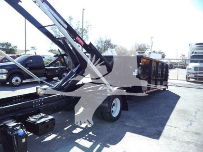 Isuzu NPRR roll-off truck with hydraulic crane in service bay showing side view and rear loading area.
