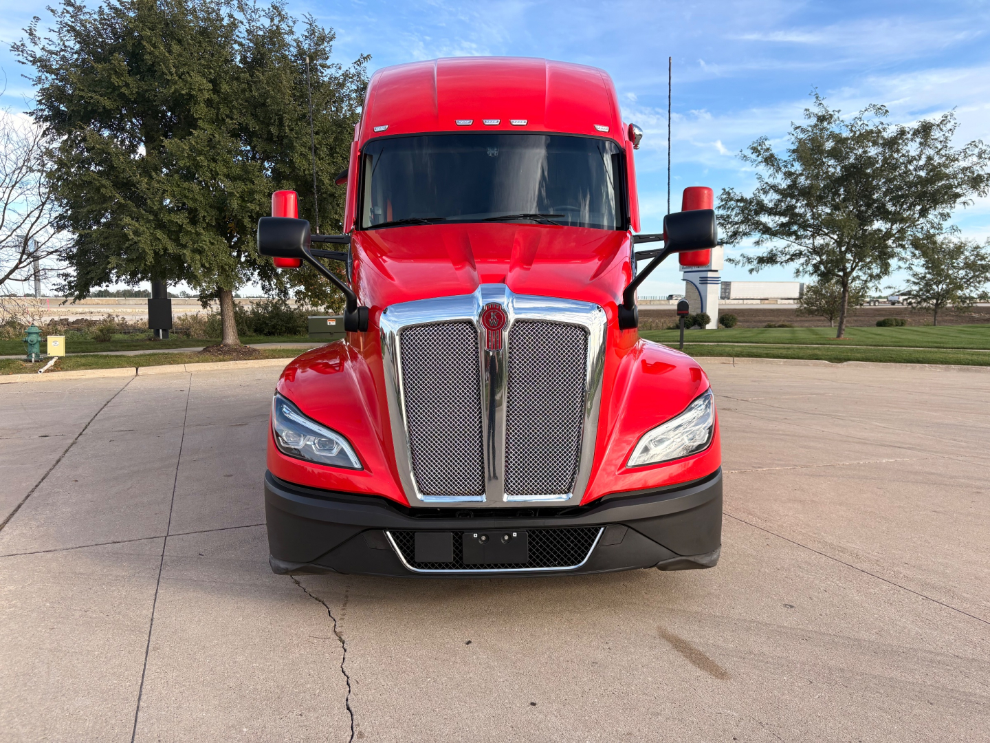 Front view of a red Kenworth T680 truck with chrome grille, black bumper, and large windshield. No legible labels or fluid reservoirs visible in the image.