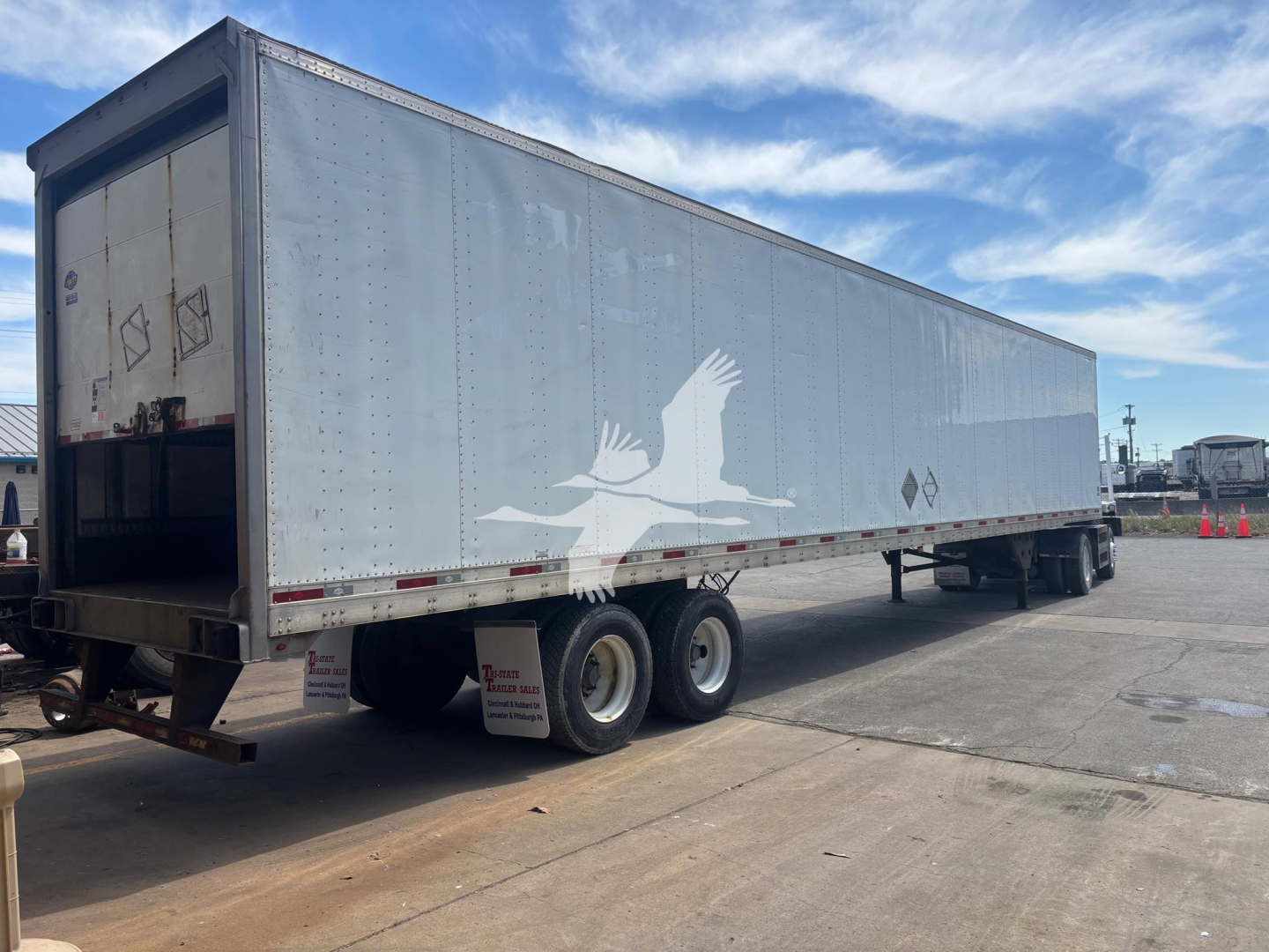 Utility 4000D-X trailer showing side decal of birds, dual rear doors, silver aluminum body, tandems, and open loading area at rear.