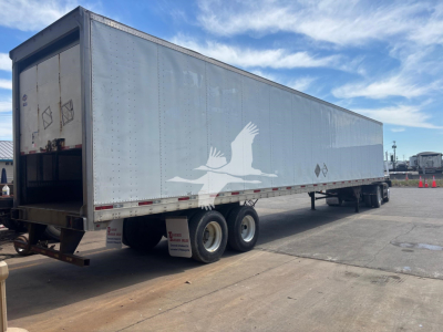 Utility 4000D-X trailer showing side decal of birds, dual rear doors, silver aluminum body, tandems, and open loading area at rear.