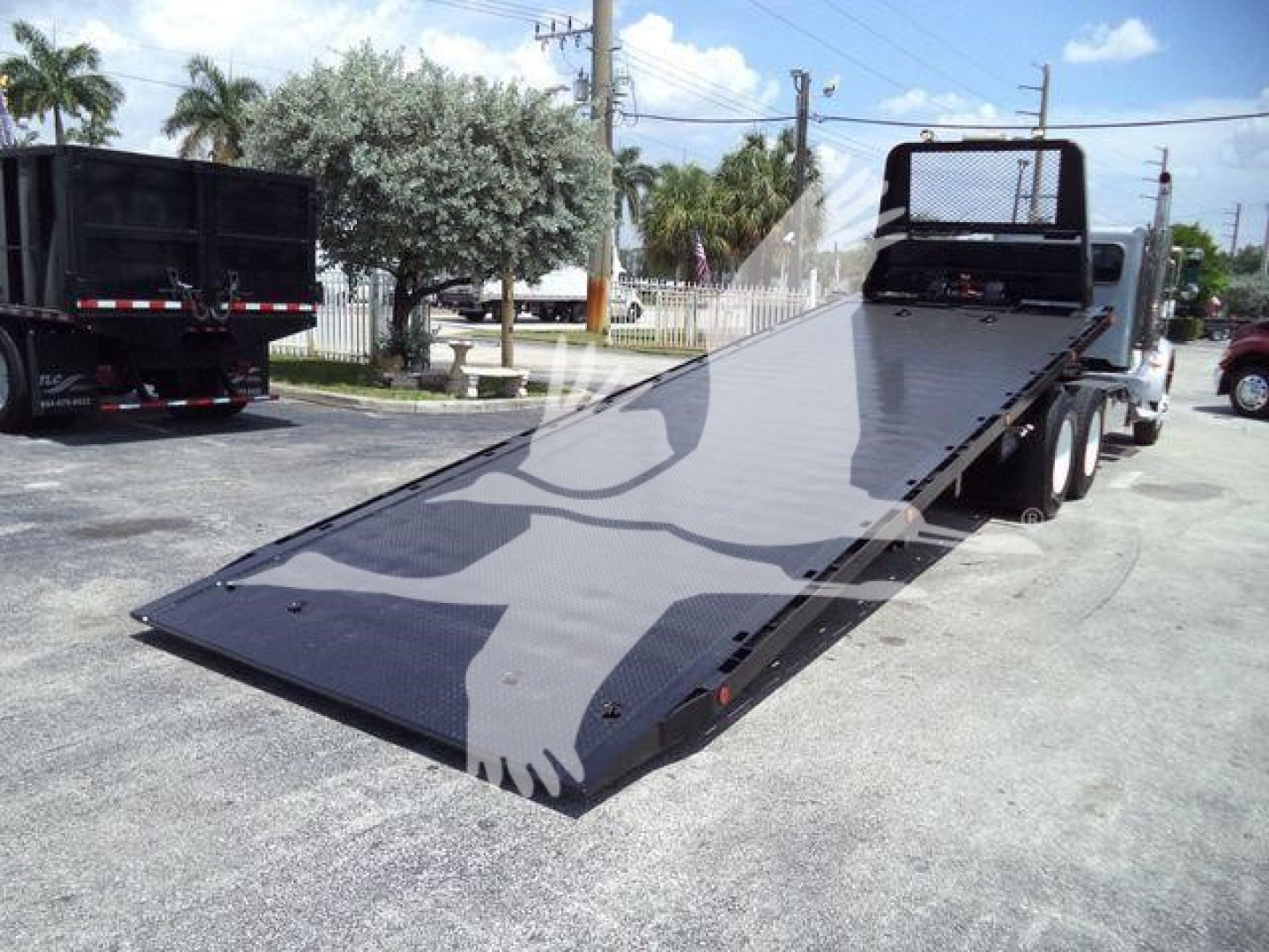 Truck rollback flatbed on a Peterbilt 348 with ramp extended, VIN tag visible, in a dealership lot.