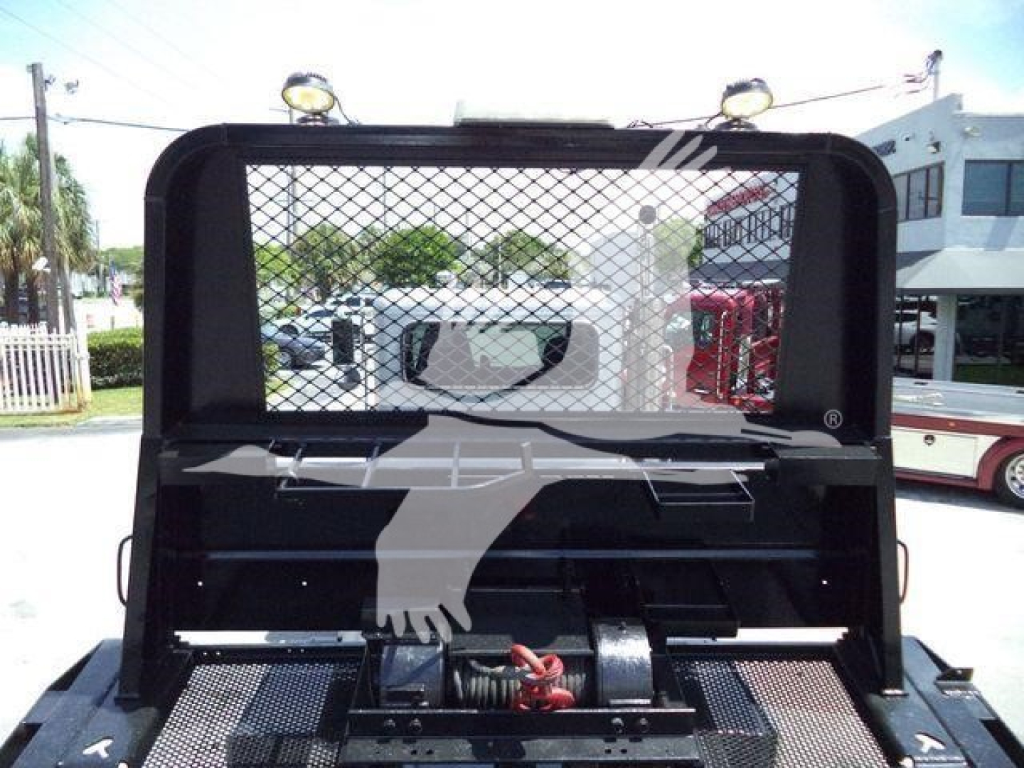 Truck bed winch setup on a Peterbilt 348 rollback unit with protective rear cage and mesh, showing equipment area and towing hardware.
