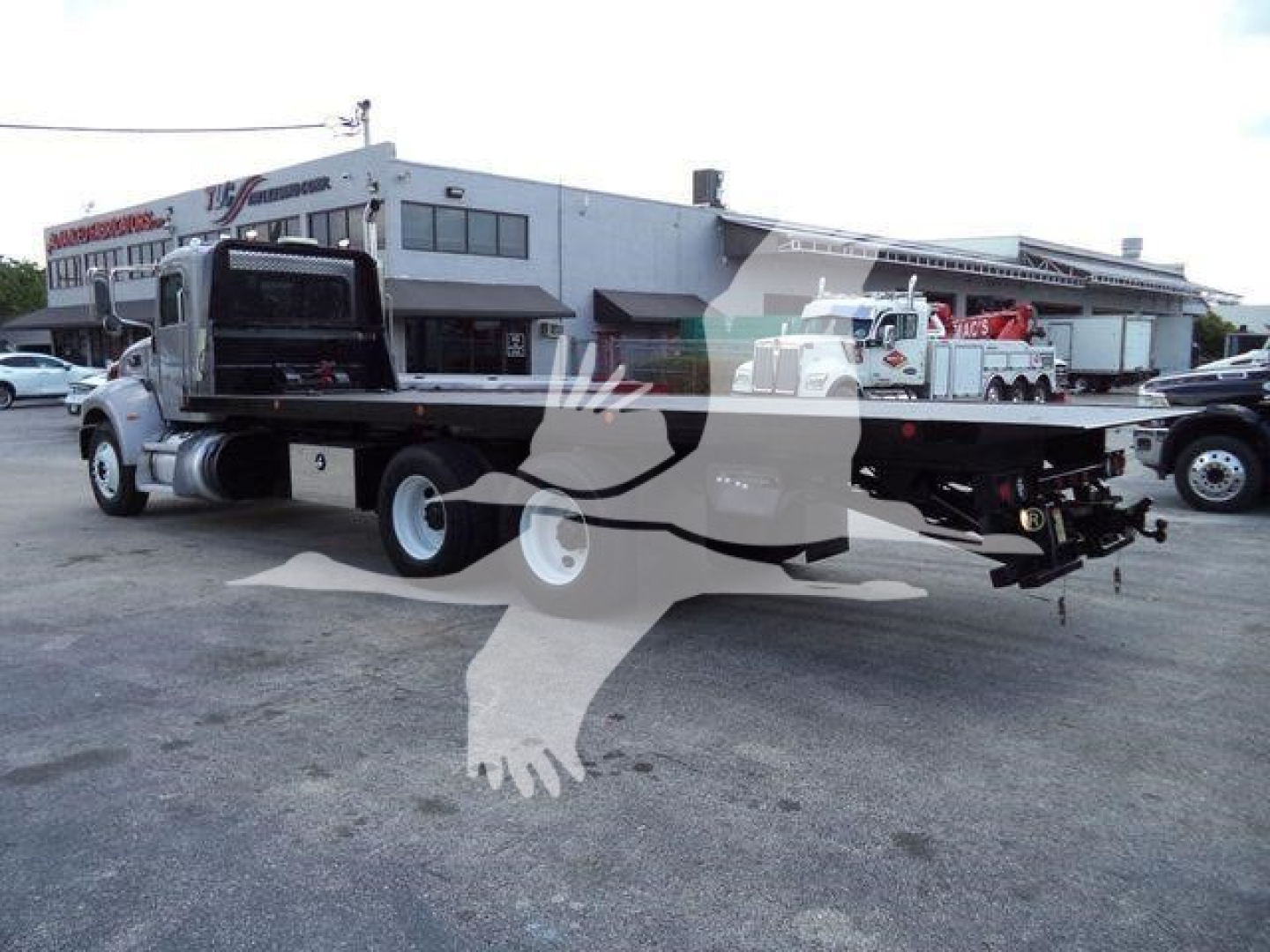 Truck chassis with rollback bed on a Peterbilt 348 in a dealership lot.