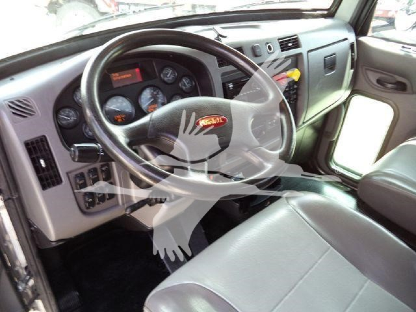 Dashboard and steering wheel of a Peterbilt 348 truck cab showing instrument cluster and Peterbilt logo on steering wheel.