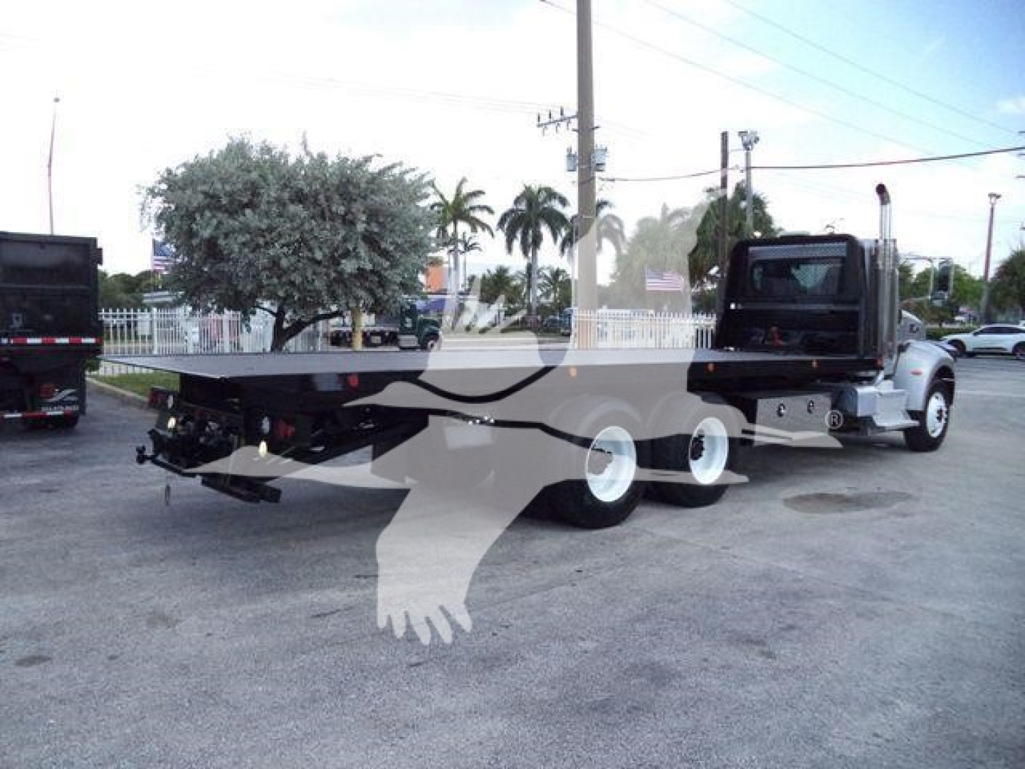Peterbilt 348 rollback truck shown from rear/side angle with flatbed and white wheels.