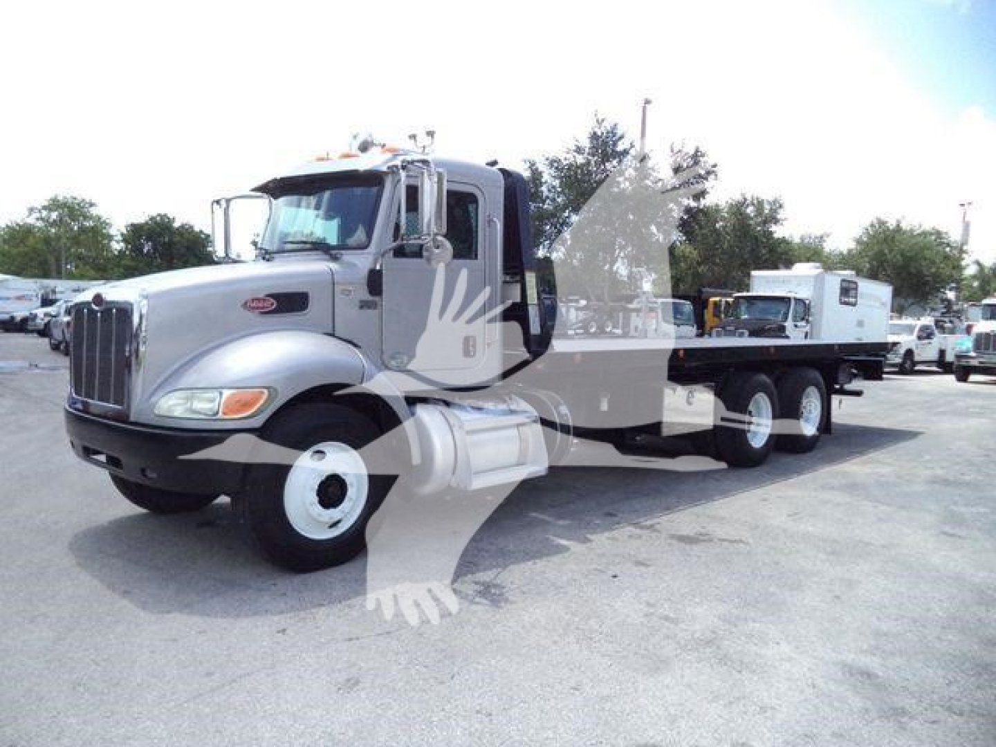 Peterbilt 348 rollback truck with long wheelbase, silver cab, chrome grille, dual rear axles, and trailer-gooseneck setup.