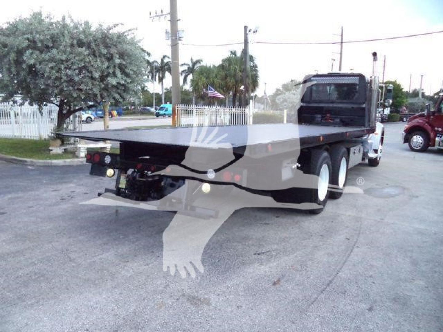Peterbilt 348 rollback truck rear view showing black flatbed and cab.