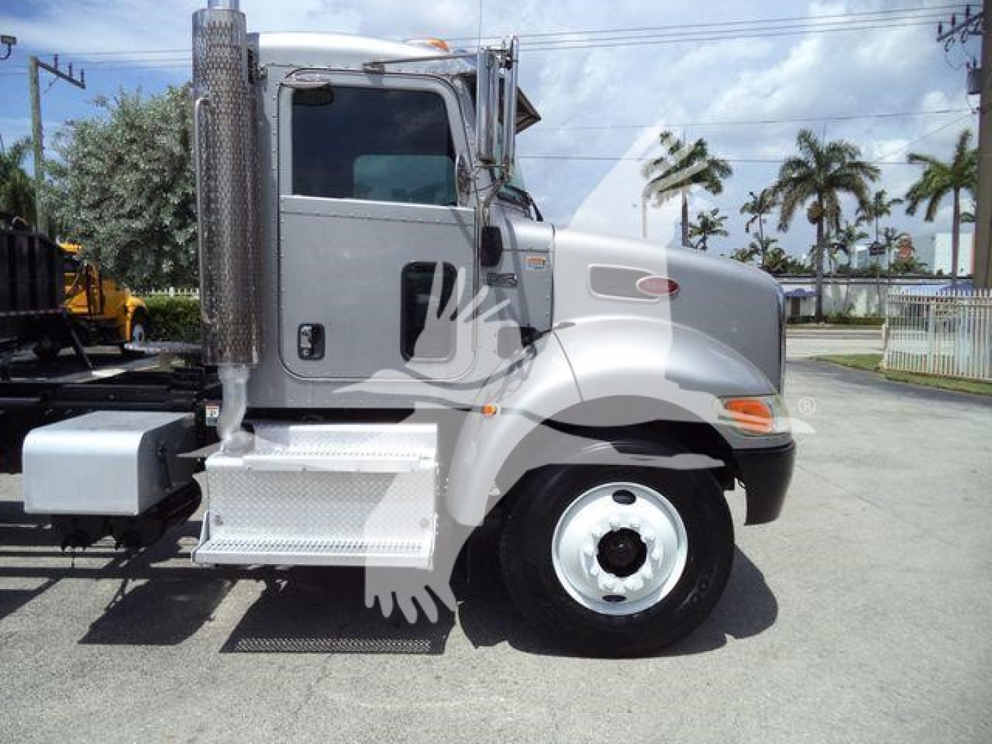 Peterbilt 348 truck side view showing cab and front wheel, with chrome exhaust stack and steps, stock number plate area visible
