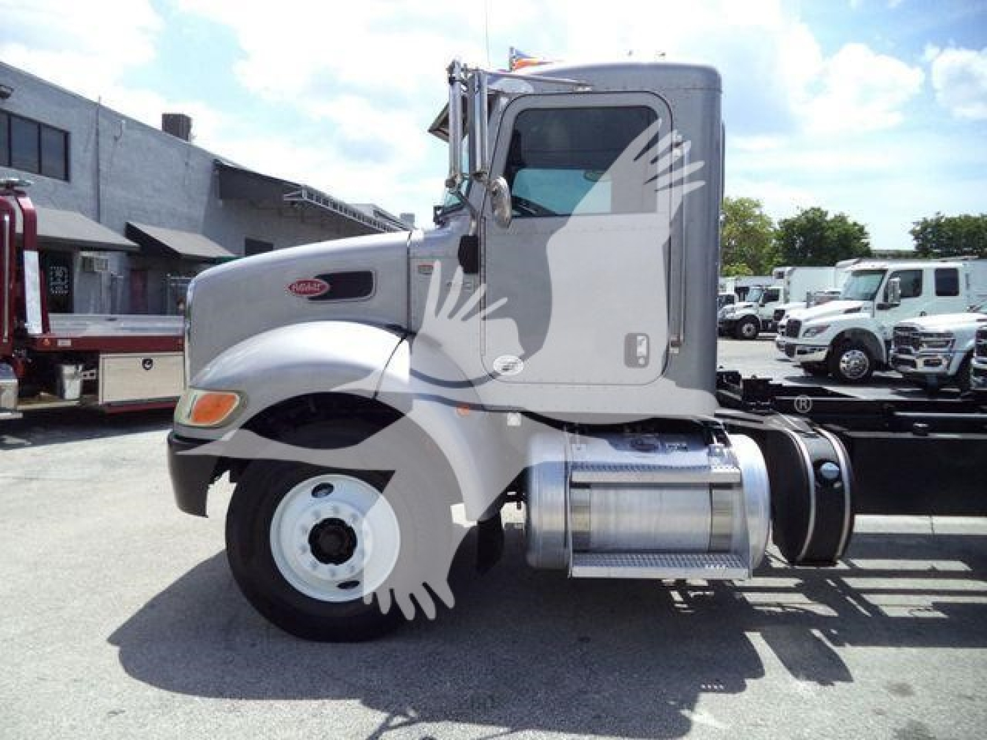 Peterbilt 348 truck cab side view showing engine bay, fuel tanks, and wheel while parked in lot.