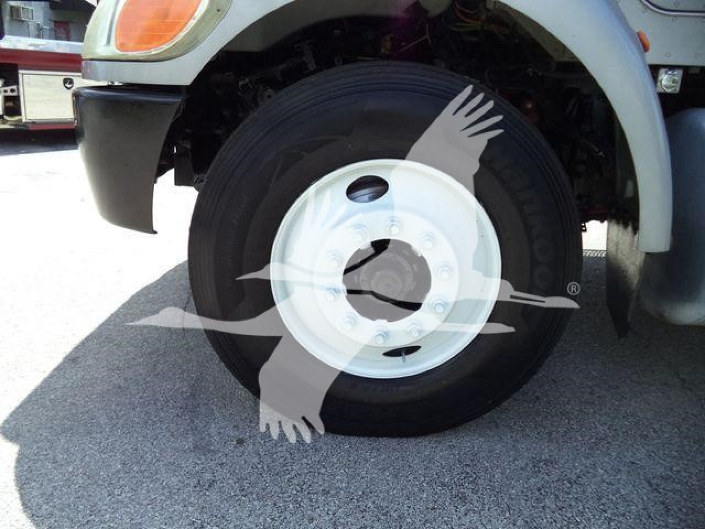 Wheel and fender of a 2015 Peterbilt 348 rollback truck with a white steel wheel, tire, and front fender.