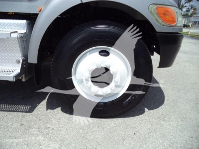 Fleet truck wheel and fender of a 2015 Peterbilt 348 rollback showing front wheel, hubcap, and part of bumper