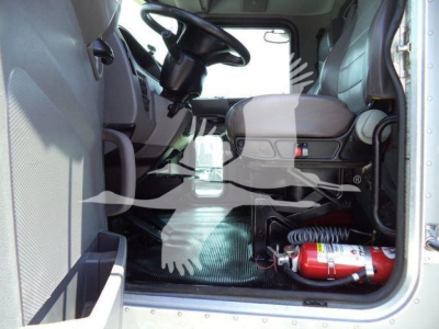 Peterbilt 348 cab interior with steering wheel, driver seat, and a red fire extinguisher in the cab floor area.