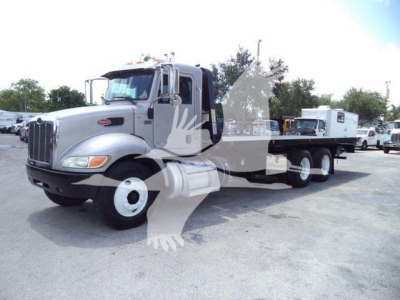 Peterbilt 348 rollback truck with long wheelbase, silver cab, chrome grille, dual rear axles, and trailer-gooseneck setup.