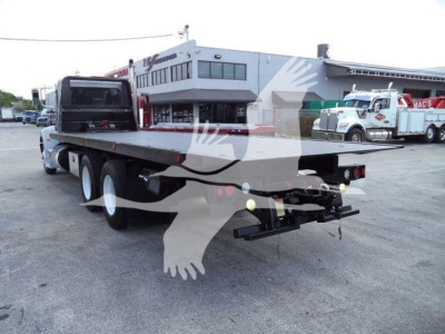 Peterbilt 348 rollback truck rear view showing flatbed and hitch, diesel chassis with triple rear axles, taillights, and reflective bumper.