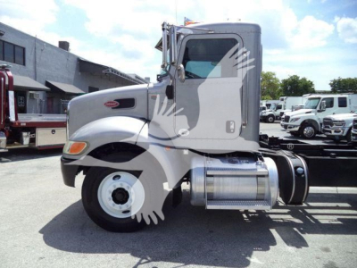 Peterbilt 348 truck cab side view showing engine bay, fuel tanks, and wheel while parked in lot.