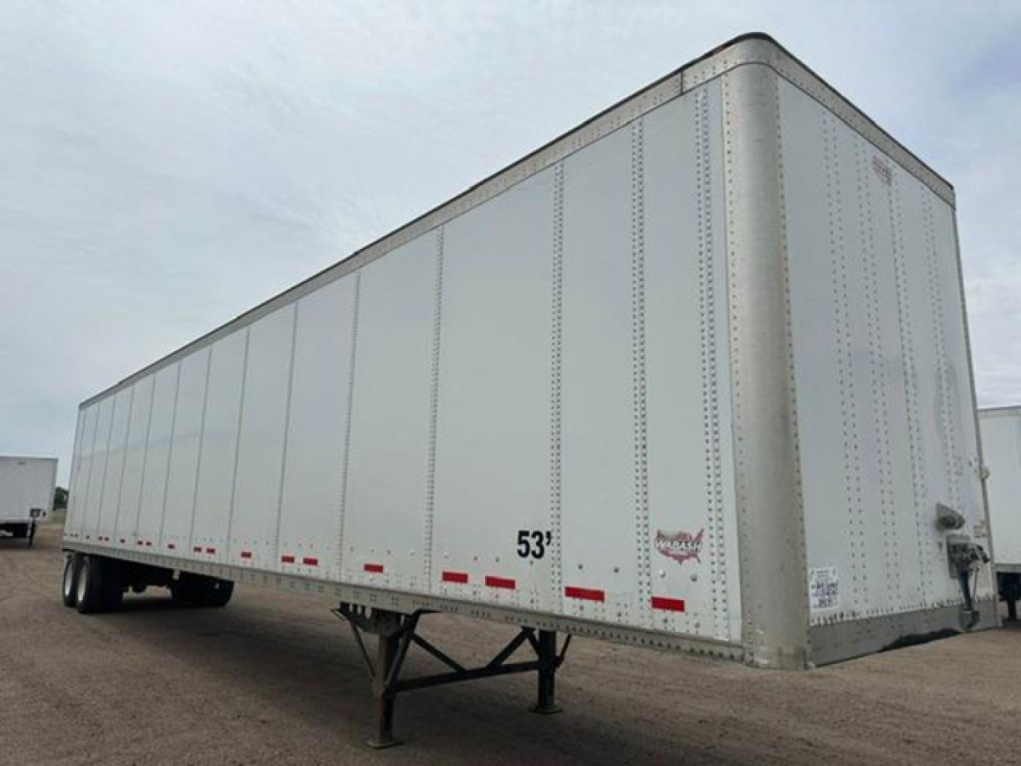 Trailer side view showing 53' Wabash van semi-trailer with white exterior and support legs at front.