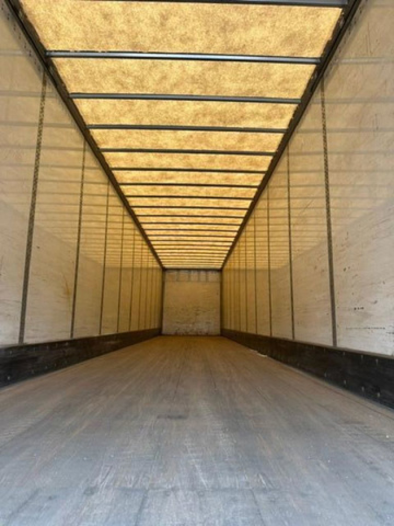 Trailer interior showing long empty cargo space with wooden ceiling ribs and metal side walls.