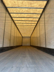 Trailer interior showing long empty cargo space with wooden ceiling ribs and metal side walls.