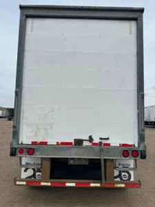 Rear view of a white Wabash van trailer showing rear bumper and lights with license plate areas and reflective tape.