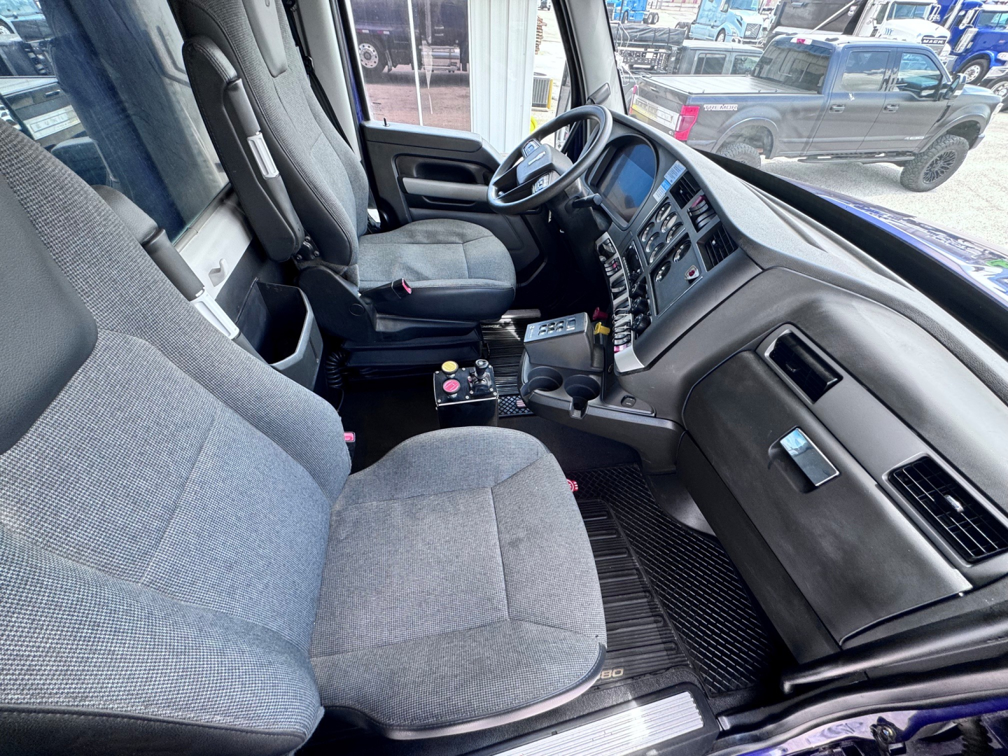 Kenworth T880 cab interior showing driver seat, steering wheel, and dashboard in view.