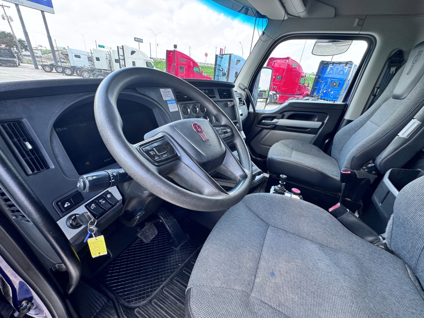 Kenworth T880 cabin interior showing steering wheel, dashboard controls, and seats.
