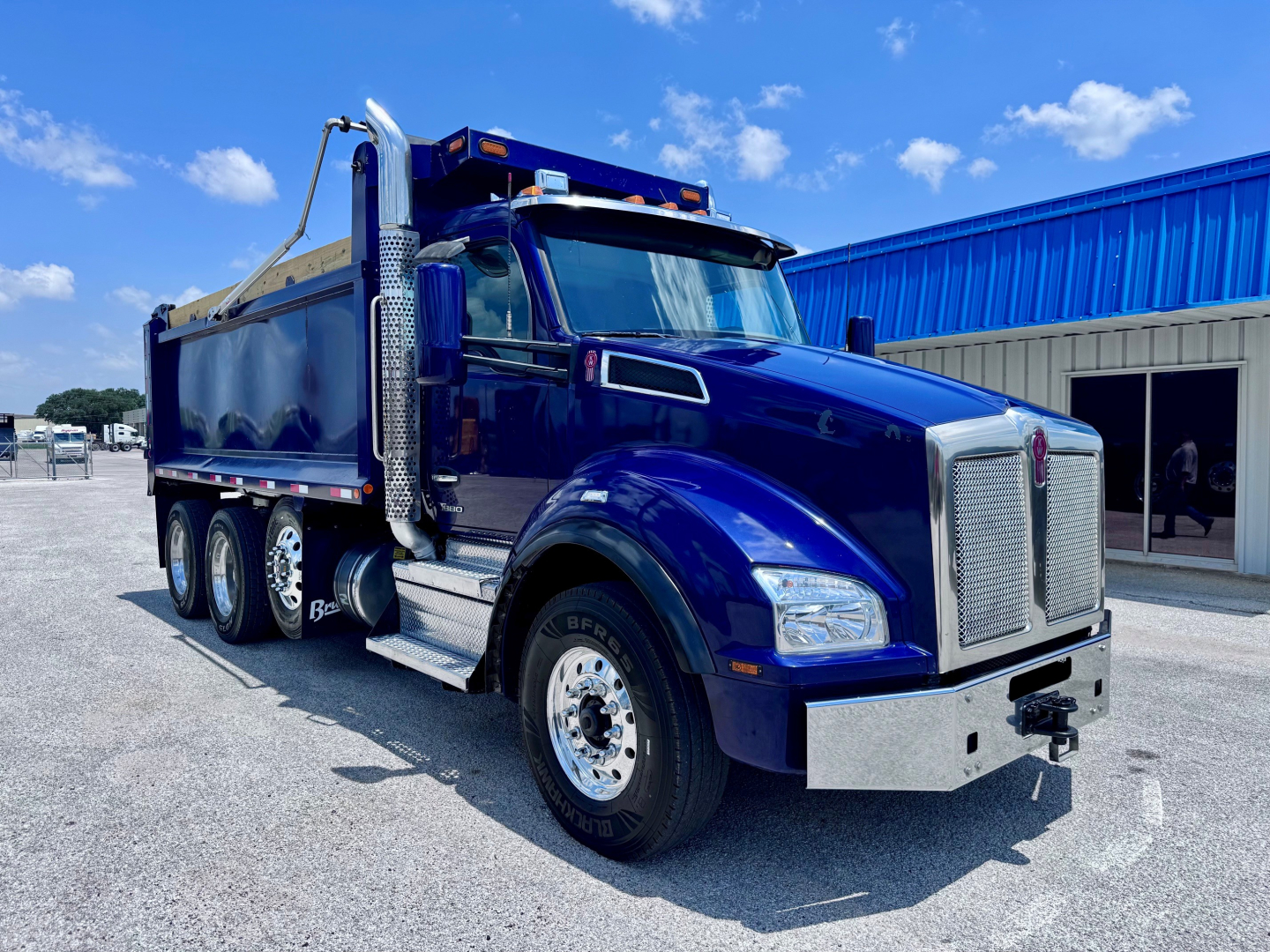 Kenworth T880 dump truck in blue showing front cab and side view with chrome bumper and black bed