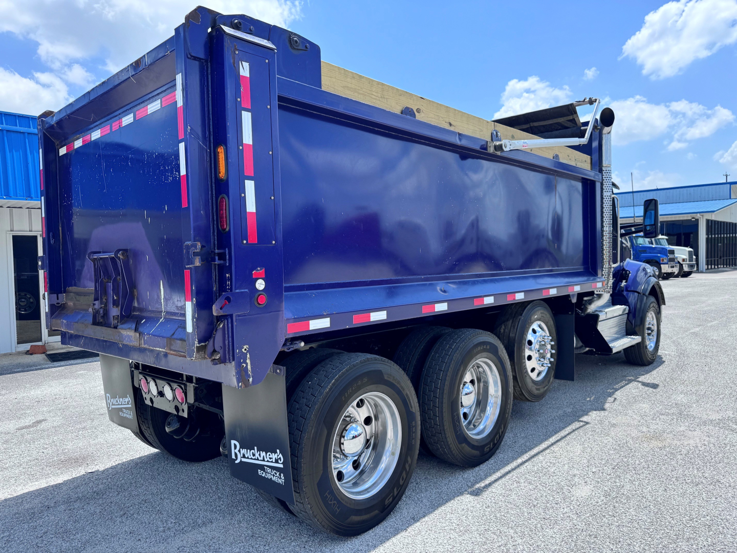 Kenworth T880 dump truck in blue, side and rear views showing dump bed and rear wheels.
