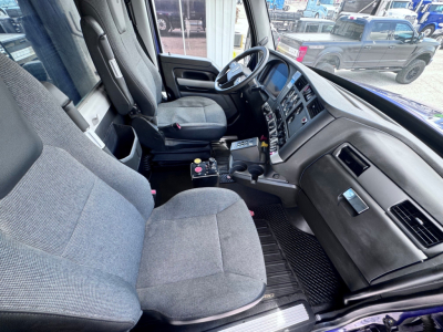 Kenworth T880 cab interior showing driver seat, steering wheel, and dashboard in view.