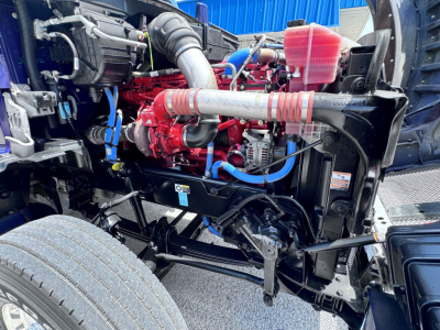 Kenworth T880 engine bay showing red engine, blue hoses, and exposed chassis with coolant reservoir