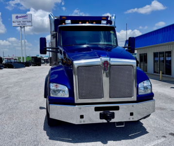 Kenworth T880 dump truck front view showing bold chrome grille and blue cab with bumper and headlights.