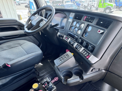 Kenworth T880 cab interior showing steering wheel, instrument cluster, center console with switches, and gear/shifter. Dashboard gauges and cup holders visible.