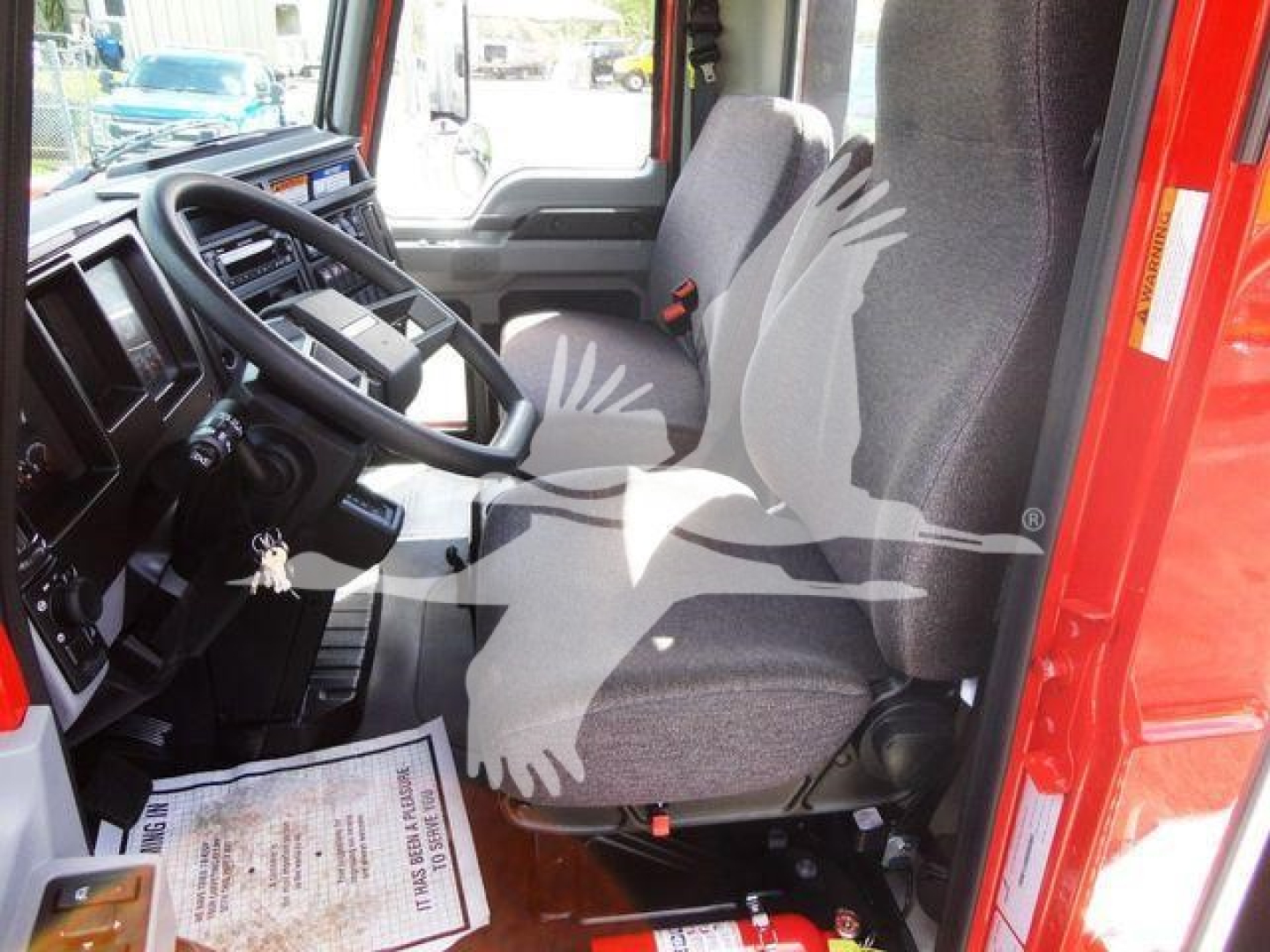 Interior of a 2027 Mack MD6 cab showing driver seat and dashboard with steering wheel and keys in ignition.