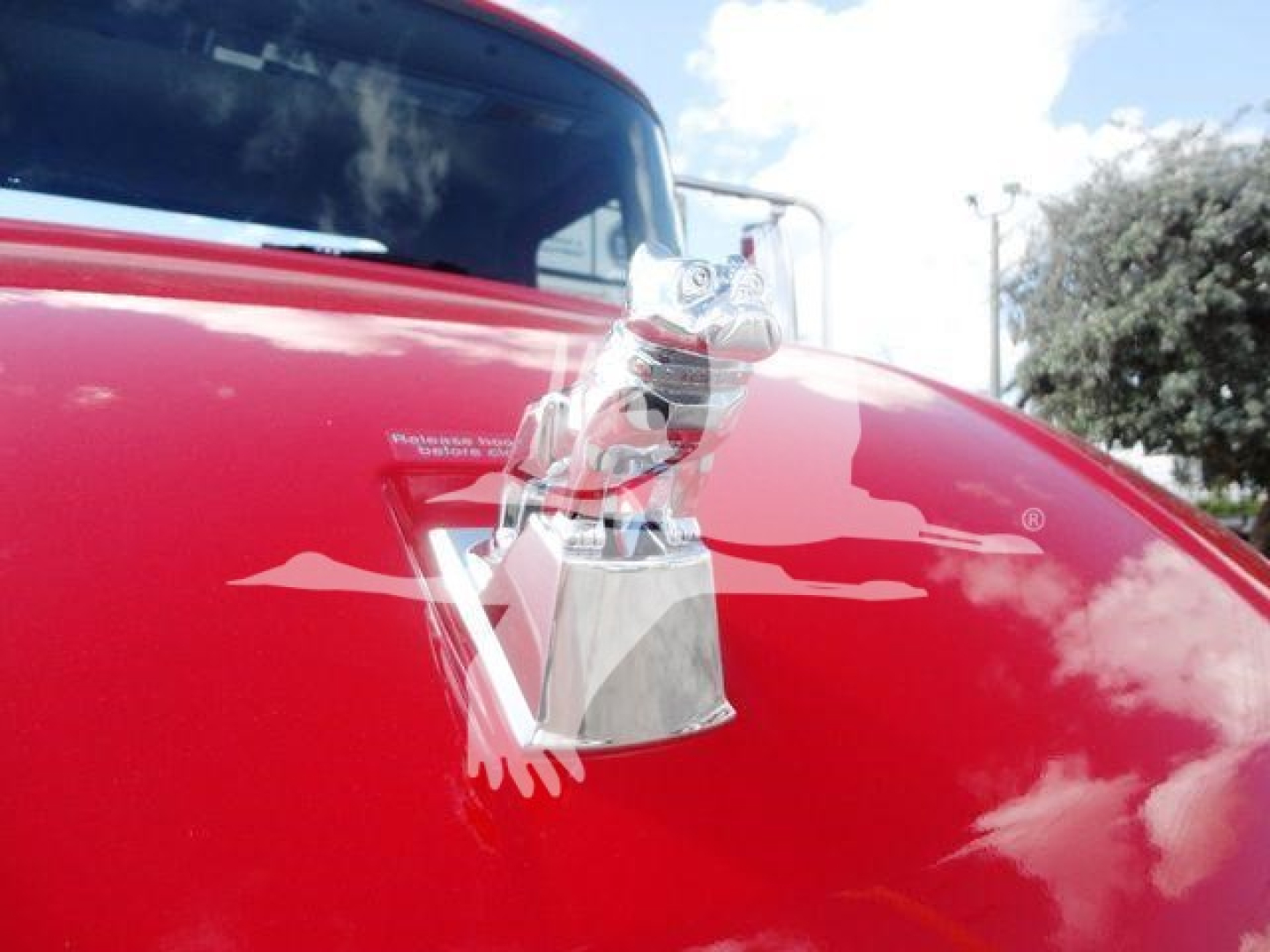 Hood of a red 2027 Mack MD6 with a chrome hood ornament visible