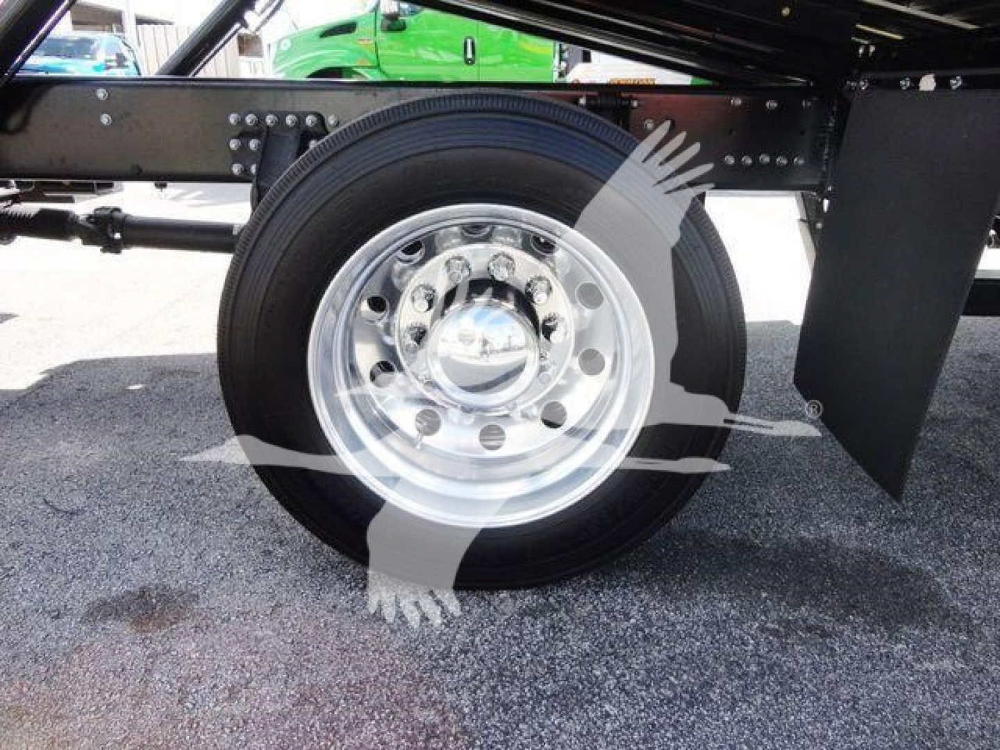 Wheel and suspension of a Mack MD6 truck showing a shiny chrome steel wheel and black tire. The image includes part of the chassis and mud flaps.