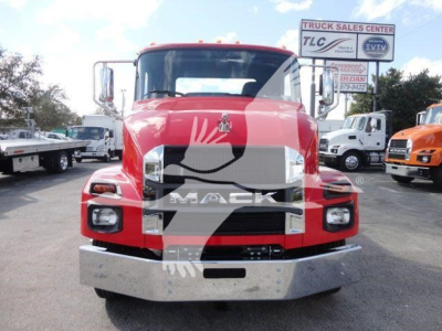 Front view of a red 2027 Mack MD6 truck in a dealership lot with chrome bumper and grille, large MACK lettering, surrounding trucks in background.
