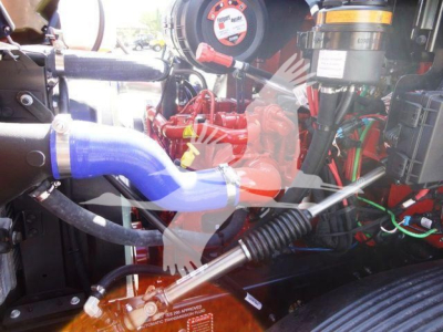 MD6 engine bay showing blue coolant hose, red engine components, black AIR/EGR hoses and wiring harness in a Mack truck engine bay.