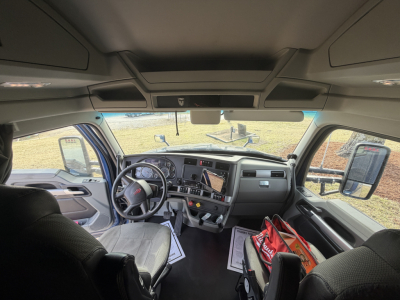 Kenworth T680 truck interior showing dashboard, steering wheel, and front seating area with center console and storage bags visible.