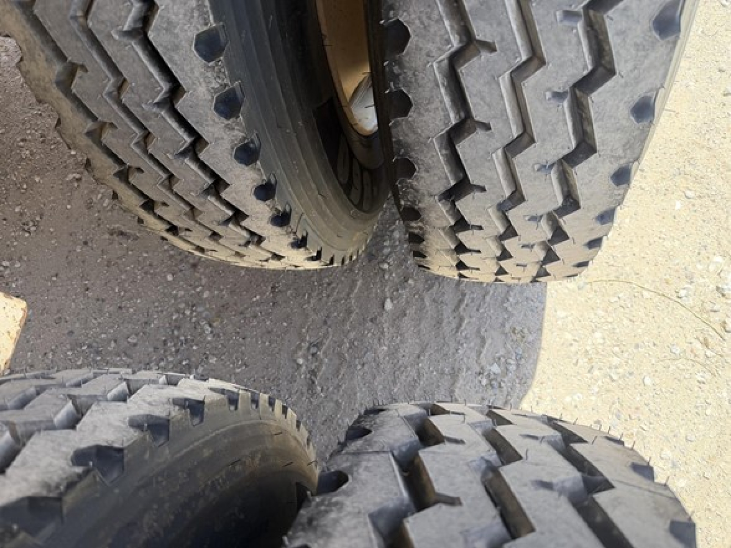 Dual rear tires of a dump trailer show rugged tread patterns and wheel hubs.