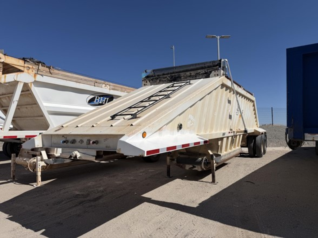 Dump trailer showing steel bottom bed and ladder on top with front hitch and dual rear axles.