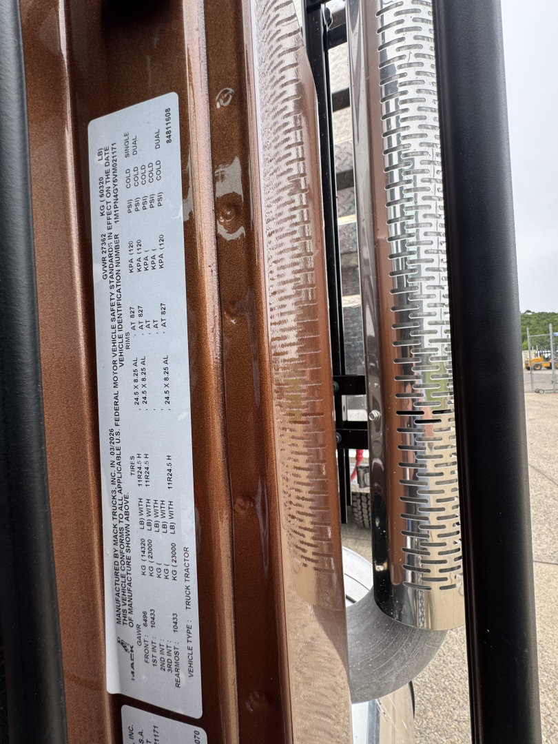 Label plate on door jamb with vehicle specs for Mack PI64T showing VIN and production details.