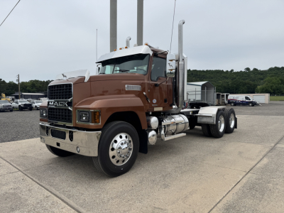 Brown 2027 Mack PI64T conventional daycab truck side view with dual exhaust stacks and chrome bumper.