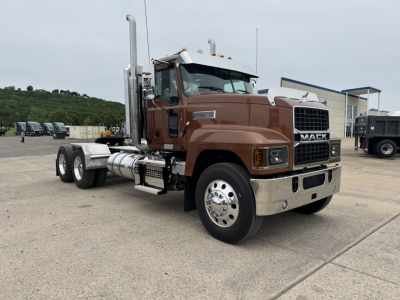 Mack PI64T conventional daycab truck side view showing brown cab and chrome bumper with dual rear axles and vertical exhaust stacks.