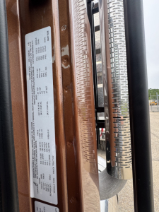 Label plate on door jamb with vehicle specs for Mack PI64T showing VIN and production details.