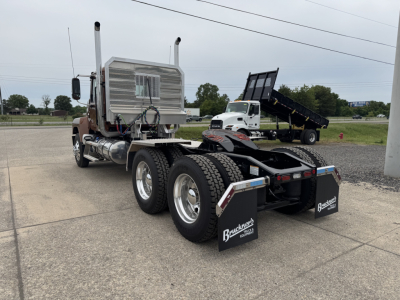 Mack PI64T tractor truck chassis showing dual rear axles with mud flaps and chrome fuel tanks.