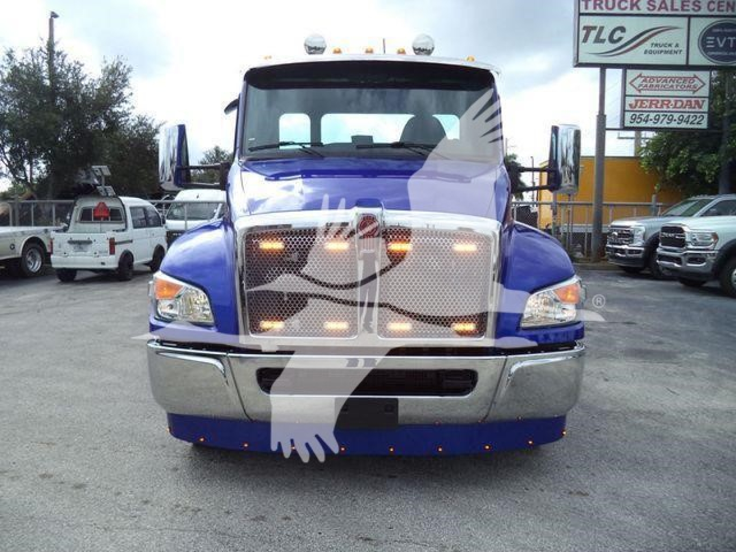 Truck front view of a blue 2025 Kenworth T280 with chrome bumper, grille, and headlights in a dealership lot