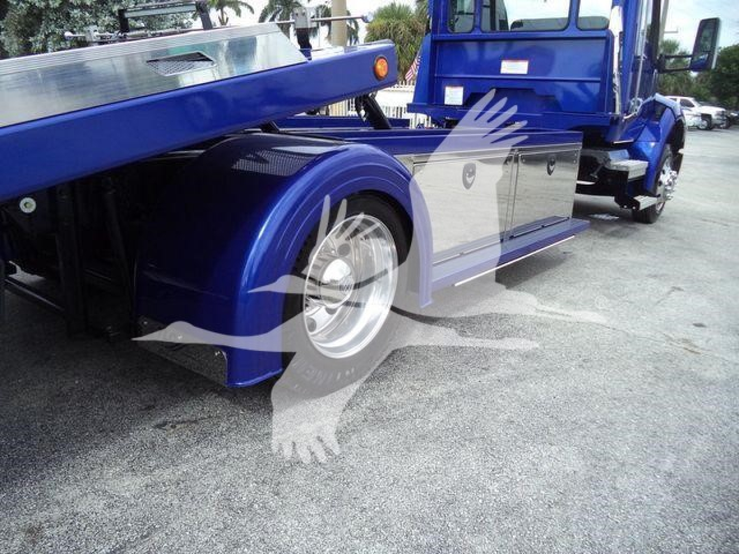 Kenworth T280 rollback truck side view showing blue chassis and wheel, with chrome accents and reflective panels.