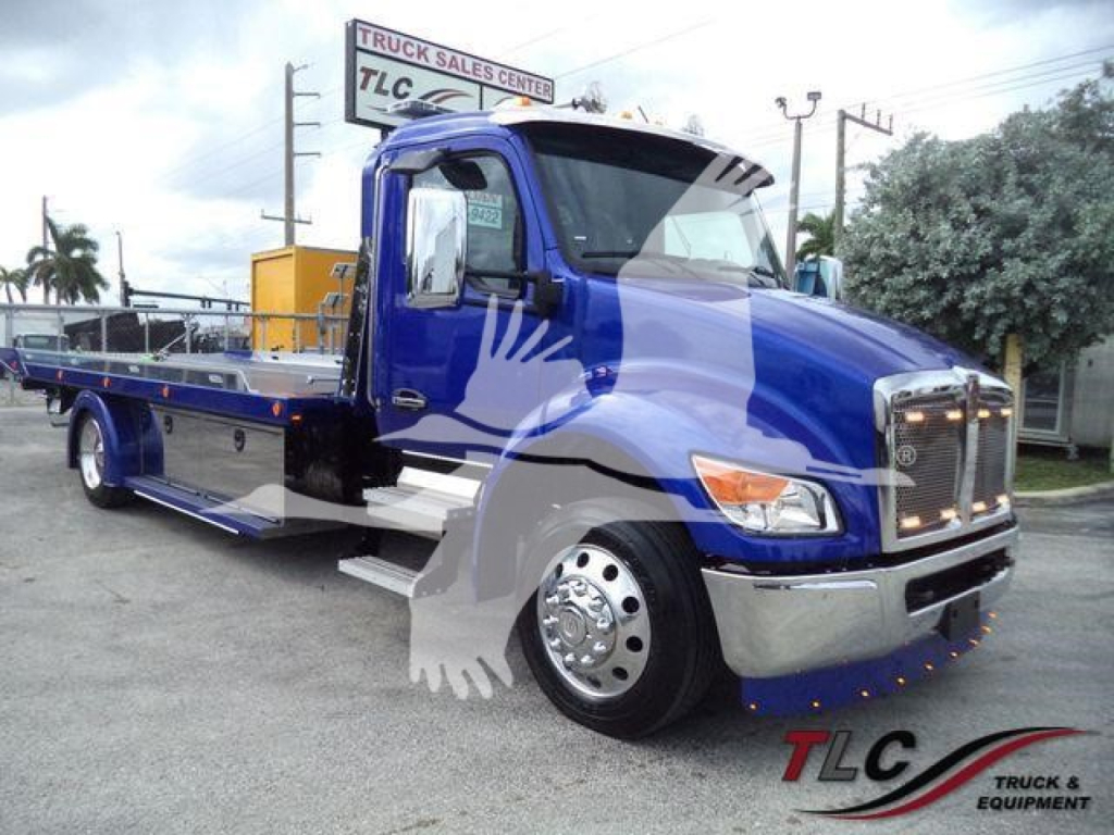 Kenworth T280 rollback truck in blue with chrome bumper and flatbed, showroom lot in background. TLC Truck & Equipment logo watermark.